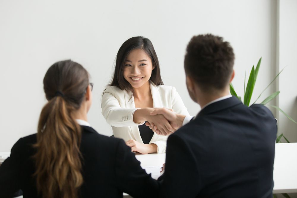 Woman in White Blazer Shaking Hands With a Man in a Suit During an Interview — People Assured Partners in Cannonvale, QLD