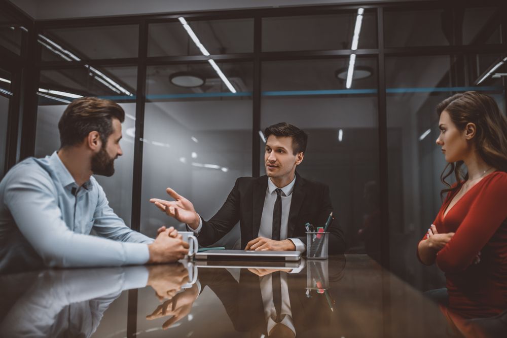 A Man in a Suit Mediates Between a Man and Woman at a Table in an Office — People Assured Partners in Rockhampton, QLD