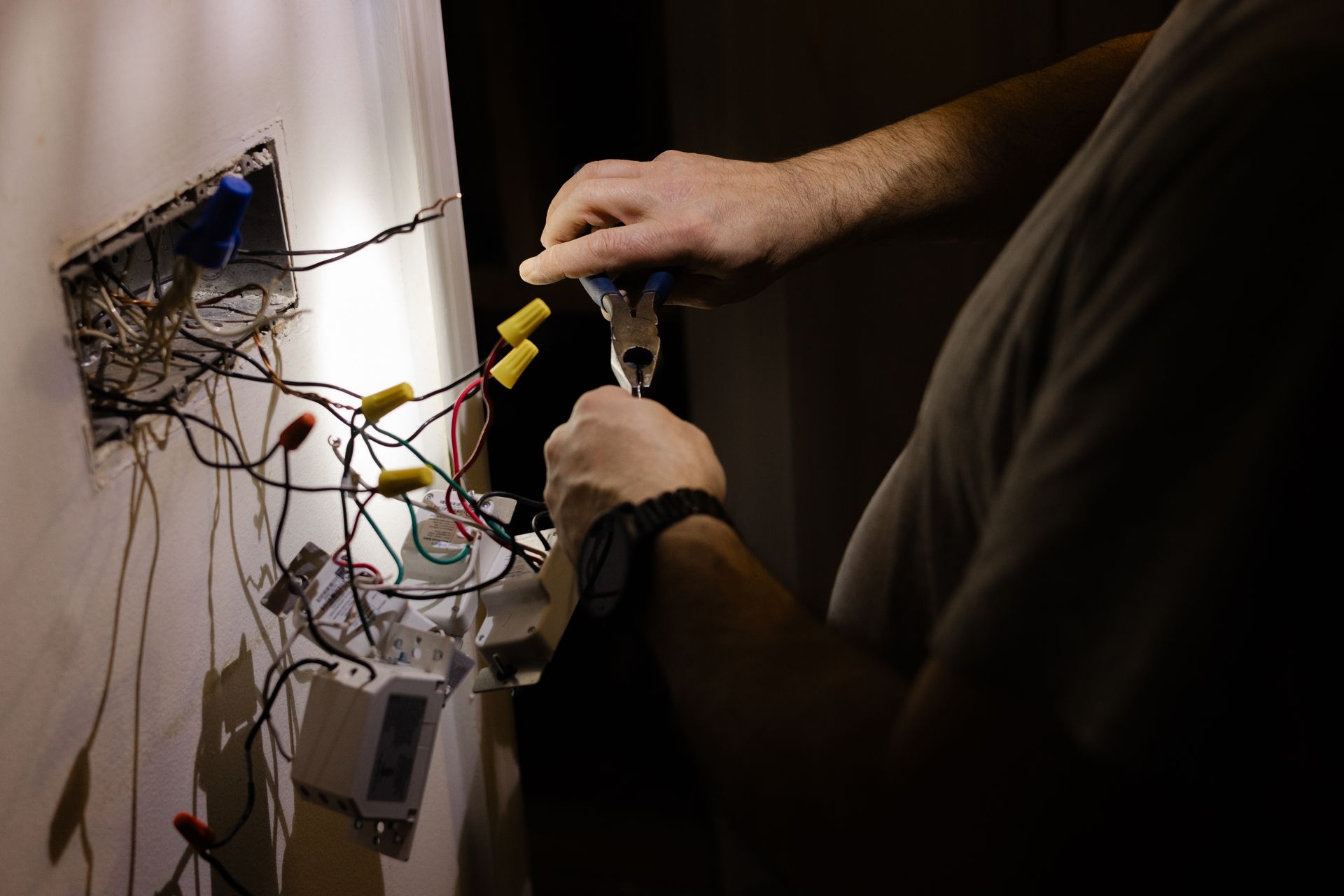 Electrician repairing exposed wiring and connections in a wall outlet. Electrician repairing exposed wiring and connections in a wall outlet.