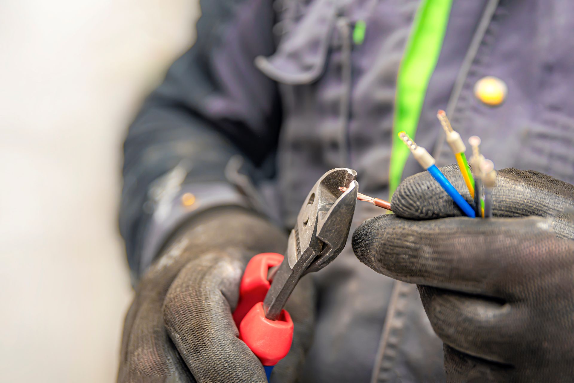 Close-up of gloved hands cutting and stripping electrical wires with pliers. Close-up of gloved hands cutting and stripping electrical wires with pliers.