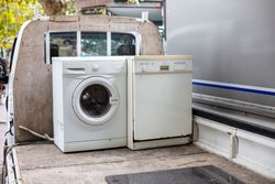 Front-load washer and dishwasher on a truck bed, suggesting appliance disposal or transport