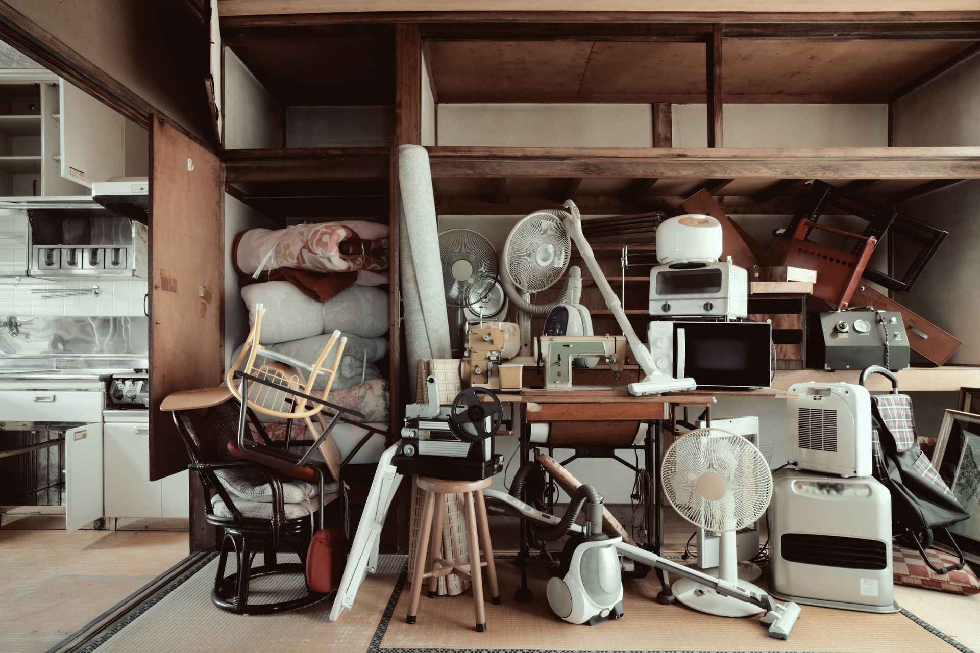 Cluttered storage room with shelves, fans, tools, and assorted household items stacked tightly together