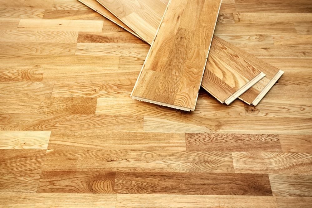 Wooden floor planks, light brown, with three loose planks on top.