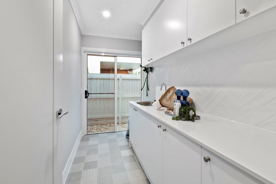 A Laundry Room With White Cabinets , A Sink , And A Sliding Glass Door — Norm Evans Floors Pty Ltd in Kunda Park, QLD