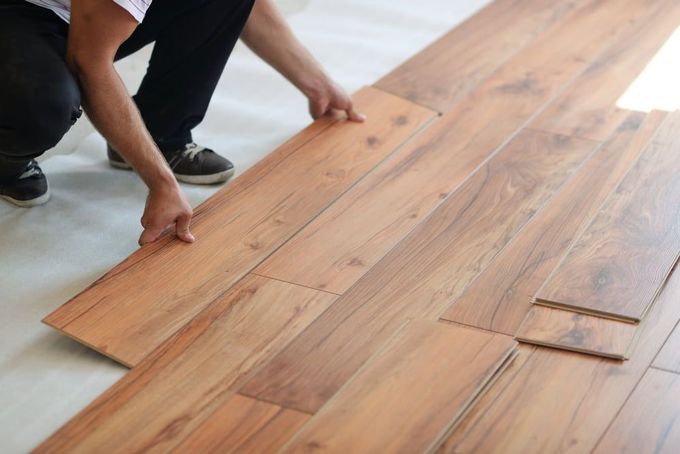 A Person Is Installing A Wooden Floor In A Room — Norm Evans Floors Pty Ltd in Kunda Park, QLD