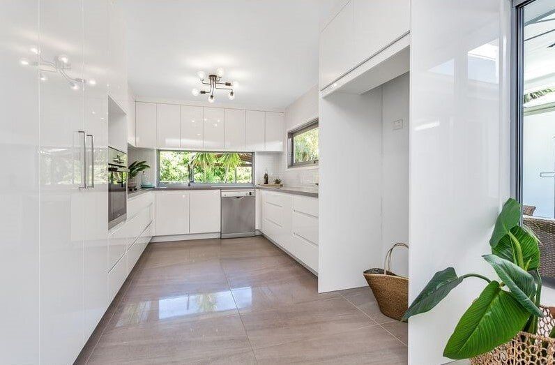 A Kitchen With White Cabinets And A Plant In The Corner — Norm Evans Floors Pty Ltd in Kunda Park, QLD