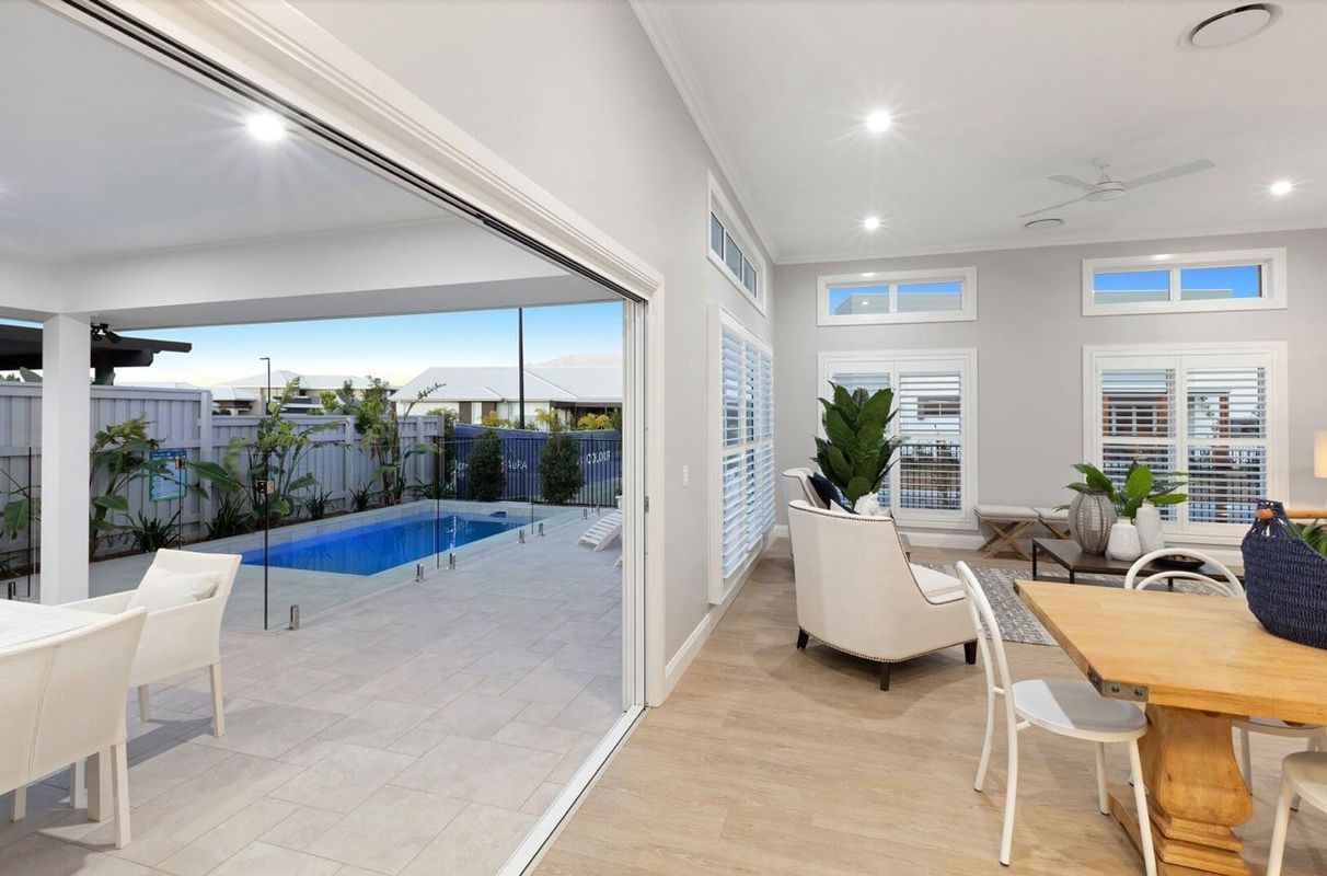 A Living Room With A Table And Chairs And A Swimming Pool In The Background — Norm Evans Floors Pty Ltd in Kunda Park, QLD