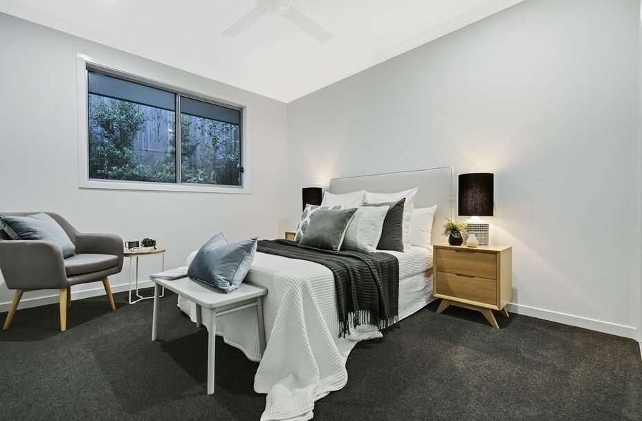 A Bedroom With A Bed , Nightstand , Chair And Window — Norm Evans Floors Pty Ltd in Kunda Park, QLD