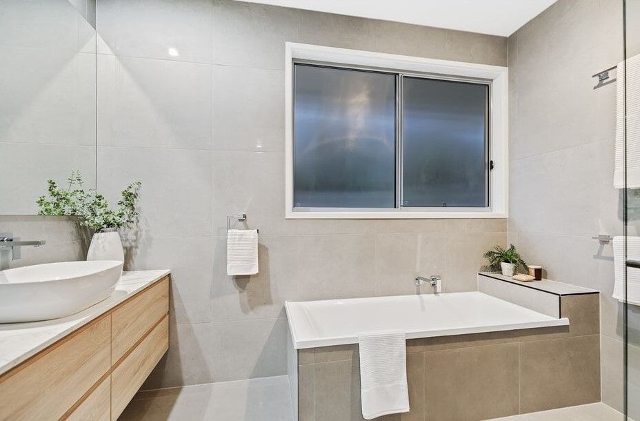 A Bathroom With A Tub , Sink , Mirror And Window — Norm Evans Floors Pty Ltd in Kunda Park, QLD