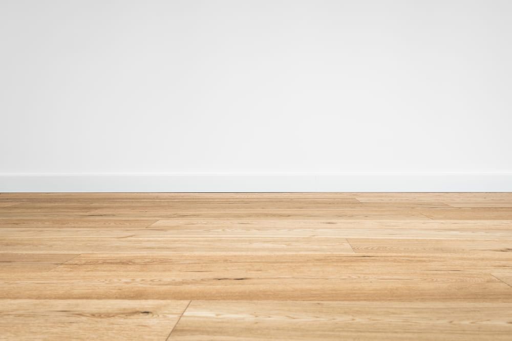 An Empty Room With A Wooden Floor And A White Wall — Norm Evans Floors Pty Ltd in Caloundra, QLD