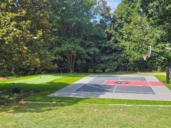 Backyard lawn with a small rectangular pool, white patio wall, and trees in the background
