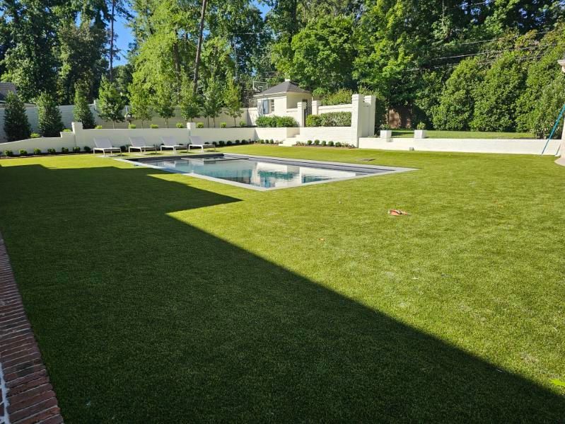 Large green lawn leading to a small gazebo, with brick steps and garden borders on either side.