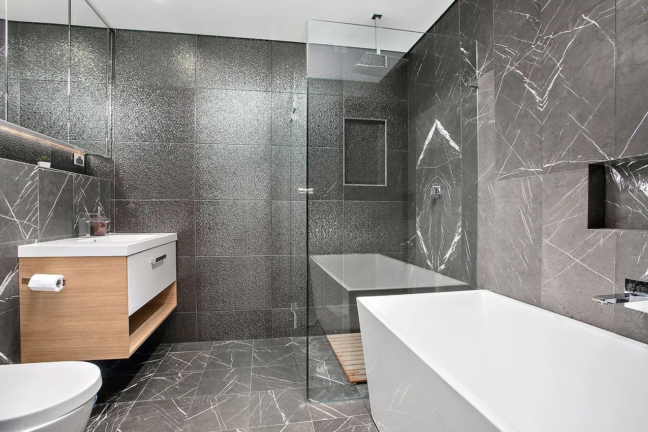 Modern bathroom with gray and white marble tiles, a floating wood vanity, and a glass shower — Corrimal Discount Tiles and Bathroomwear in East Corrimal, NSW
