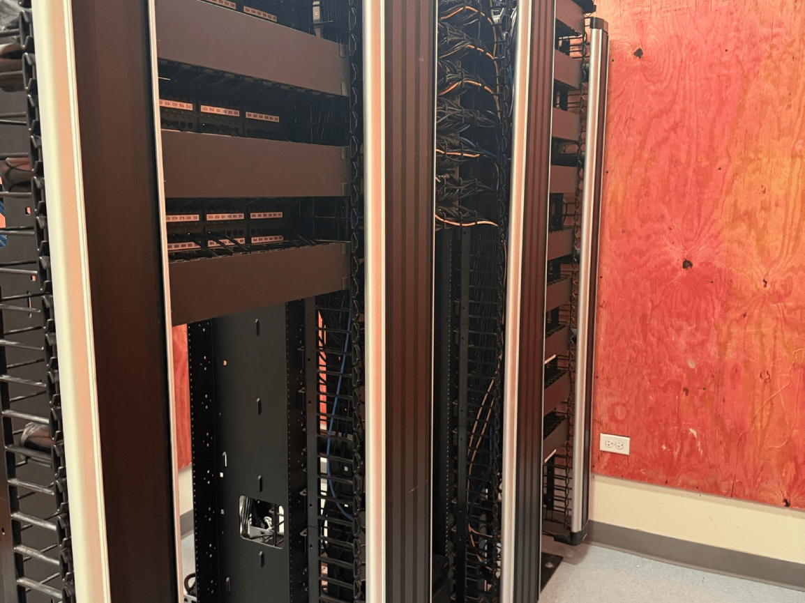 Server racks in a data center beside a red wall.