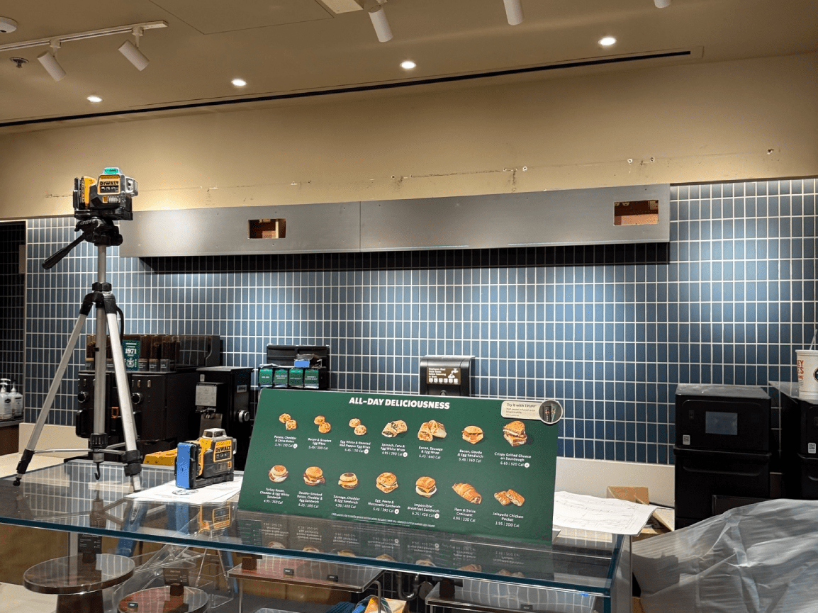 Interior with a tiled blue wall, a tripod-mounted camera, and a counter covered in a green display banner.