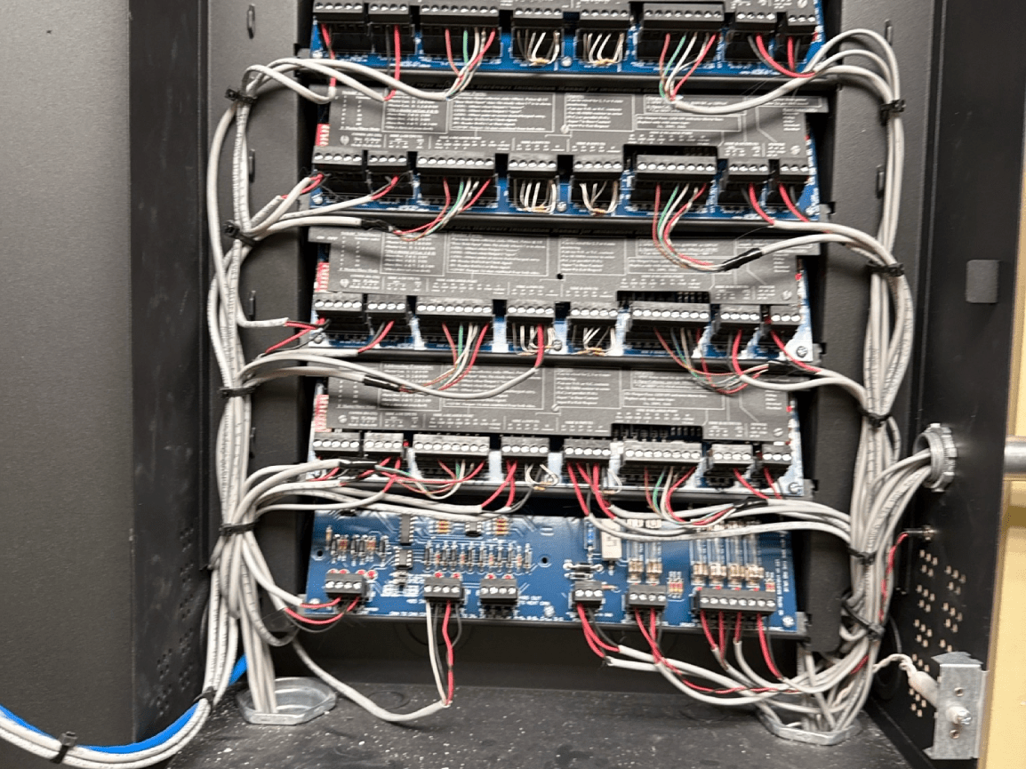 Open electrical cabinet with rows of network switches and bundled white cables