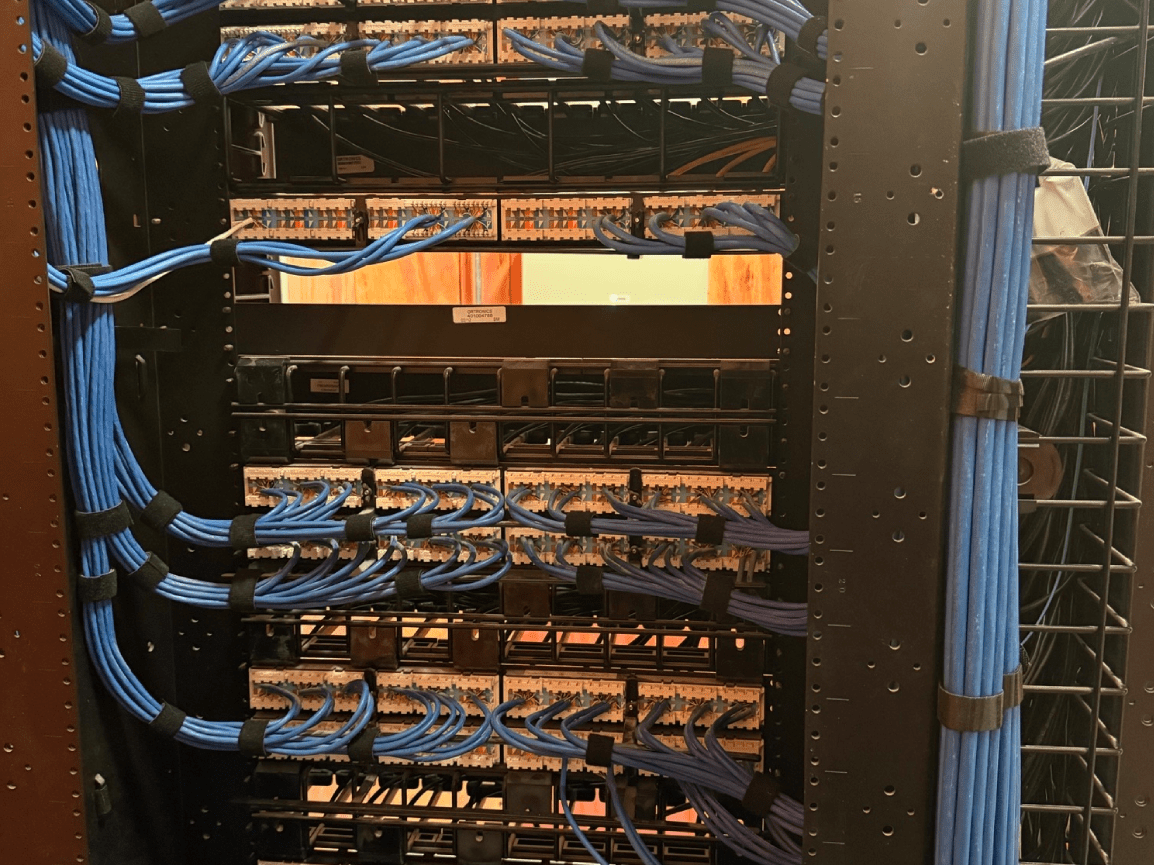 Network rack with rows of Ethernet switches and blue cables in a server room