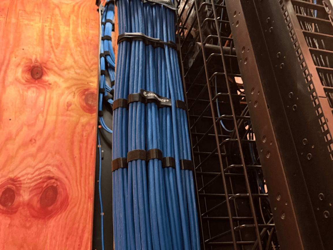 Blue cables bundled beside plywood and metal framing in a construction area