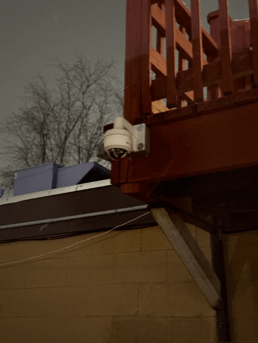 Security camera mounted on a roof edge beside a wooden deck