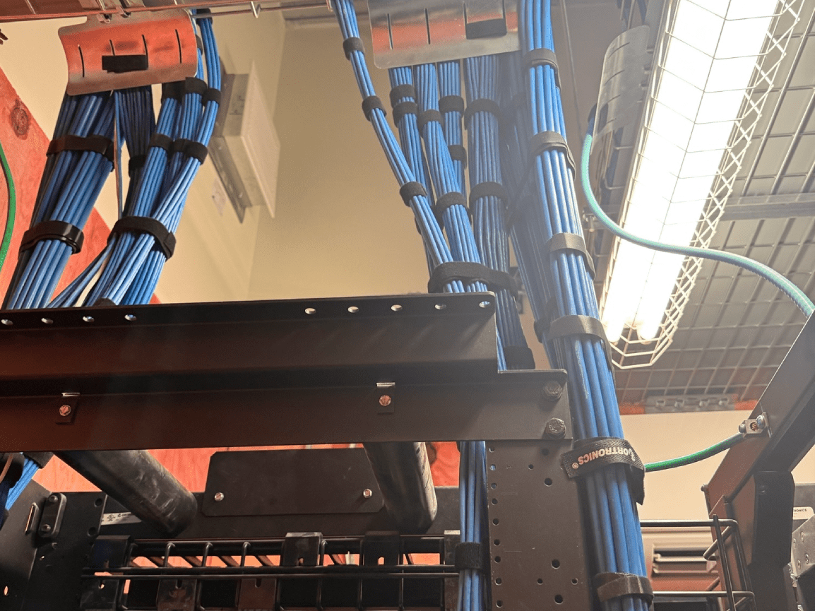 Cable bundles and metal racks beneath bright industrial lights in a server room