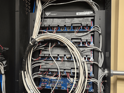 Open network cabinet with stacked switches and tangled white and black cables