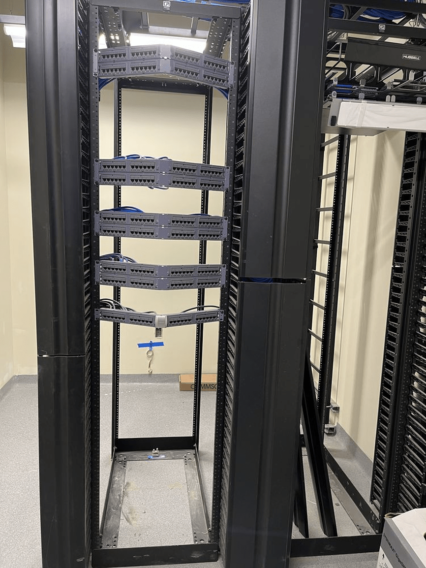 Black metal server rack with empty shelves in a data center aisle