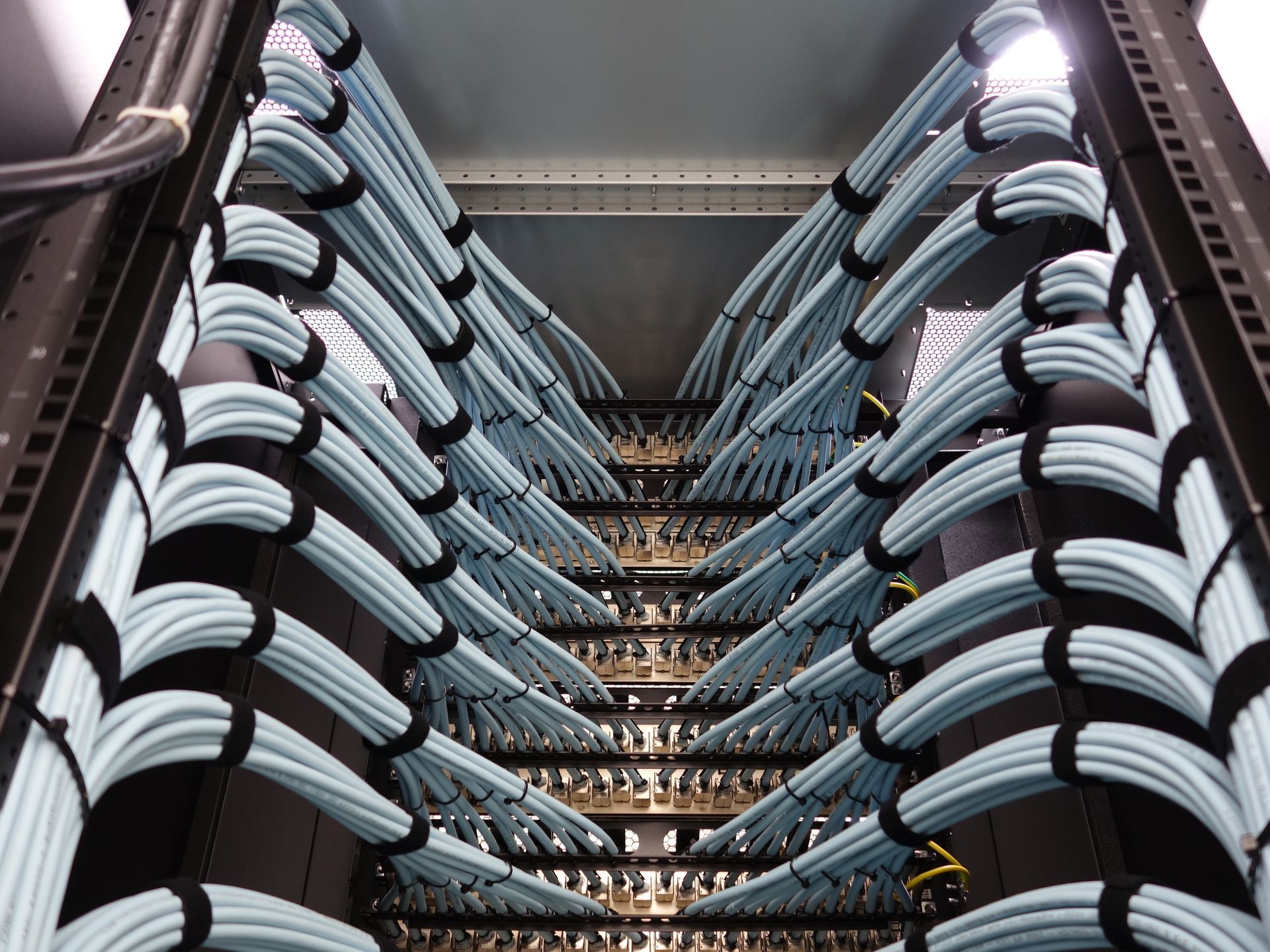 Rows of stacked chairs in a storage rack, viewed from below in an indoor space