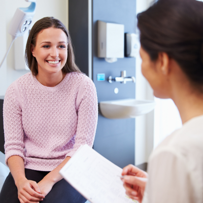 Woman in pink sweater smiles during a consultation in a clinic office