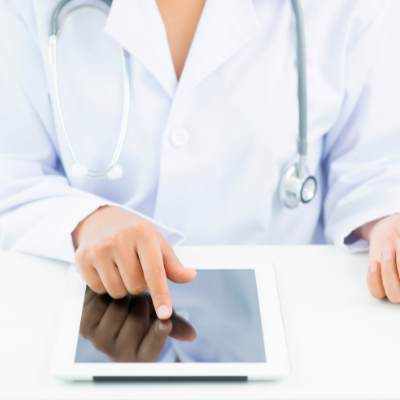 Doctor in white coat using a tablet on a desk