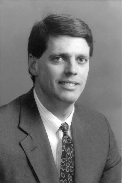 Studio portrait of Jack Ross in a suit and tie against a plain gray background