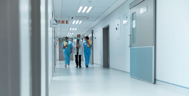 Hospital corridor with medical staff in blue scrubs walking down a bright hallway