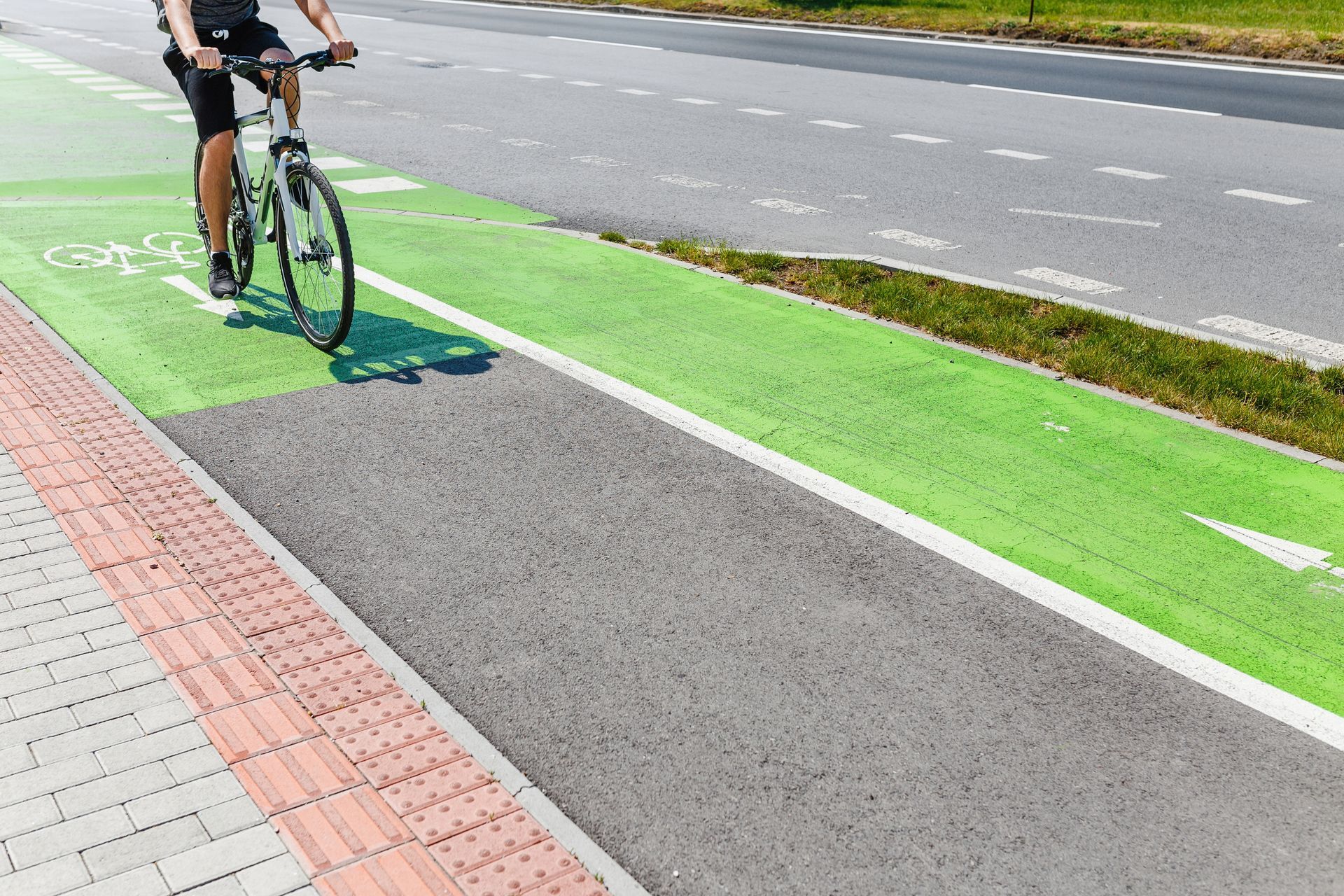 A man is riding a bike on a green bike lane.