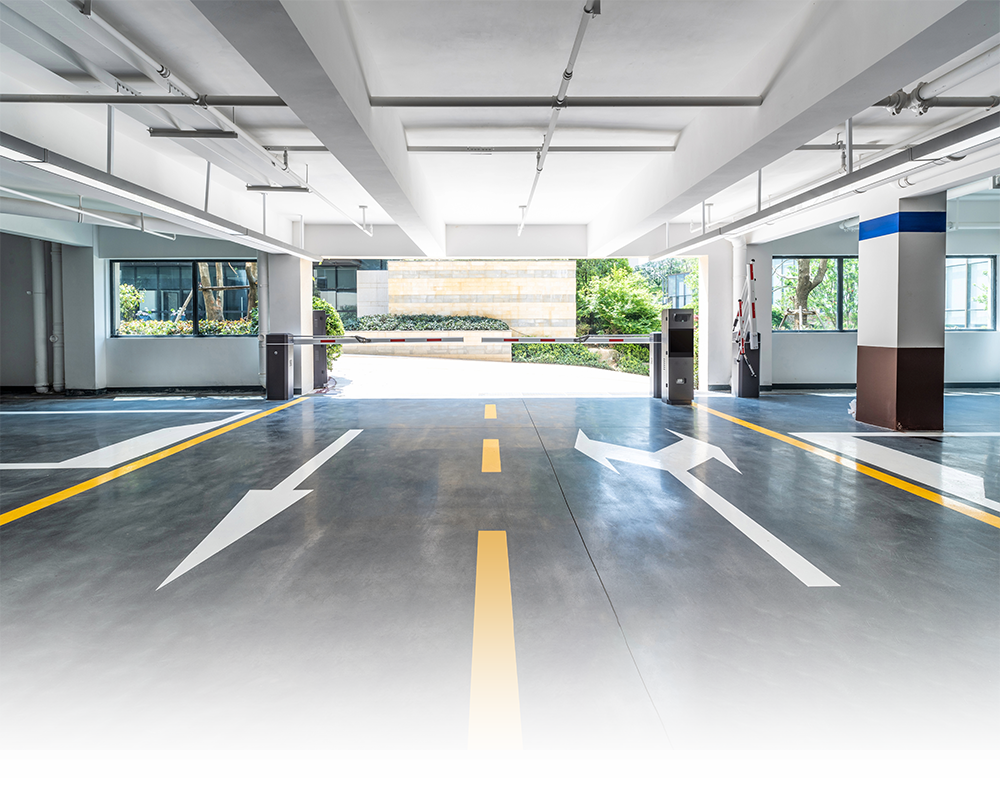 A parking garage with arrows on the floor and a gate.