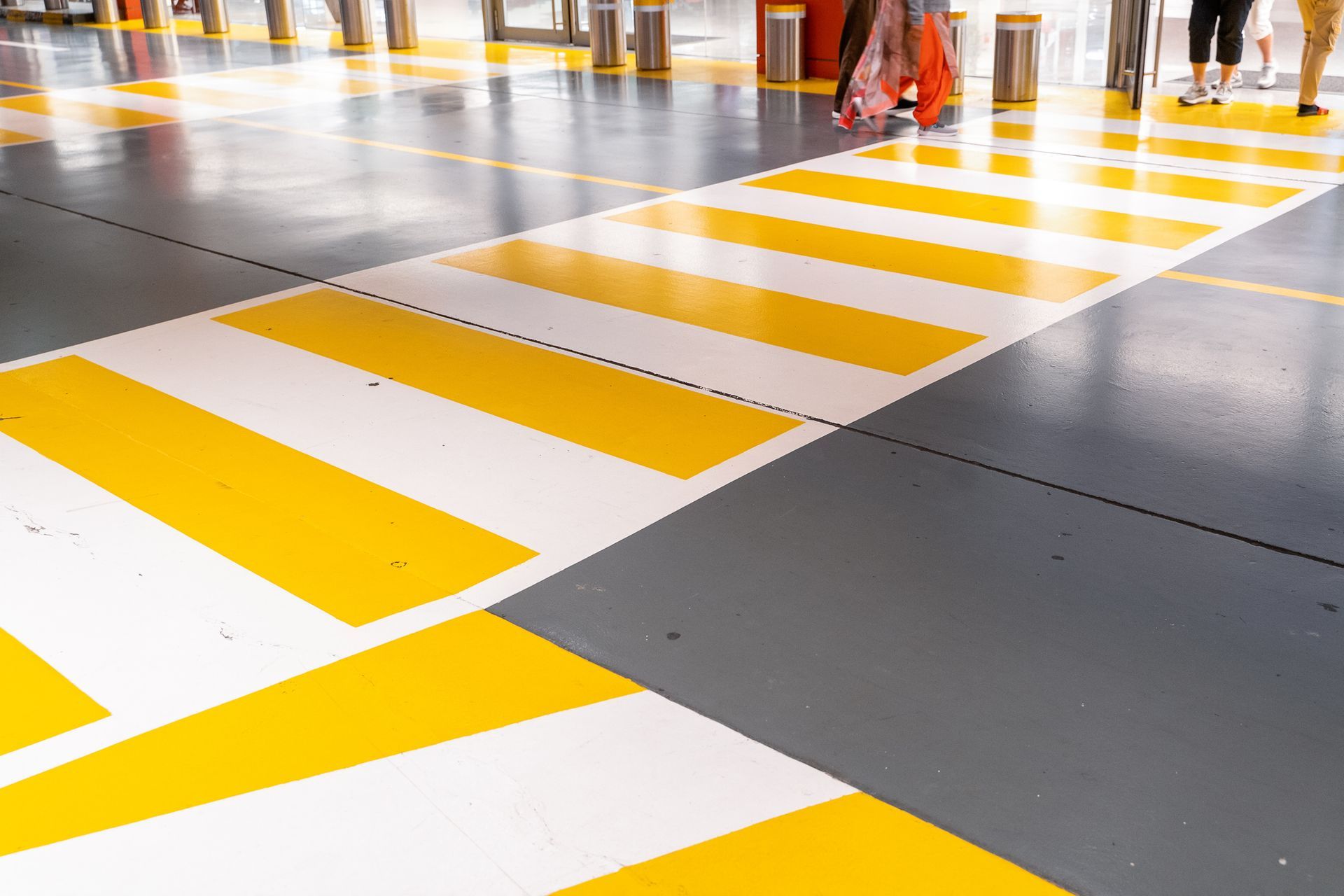 A yellow and white striped crosswalk in a parking garage.