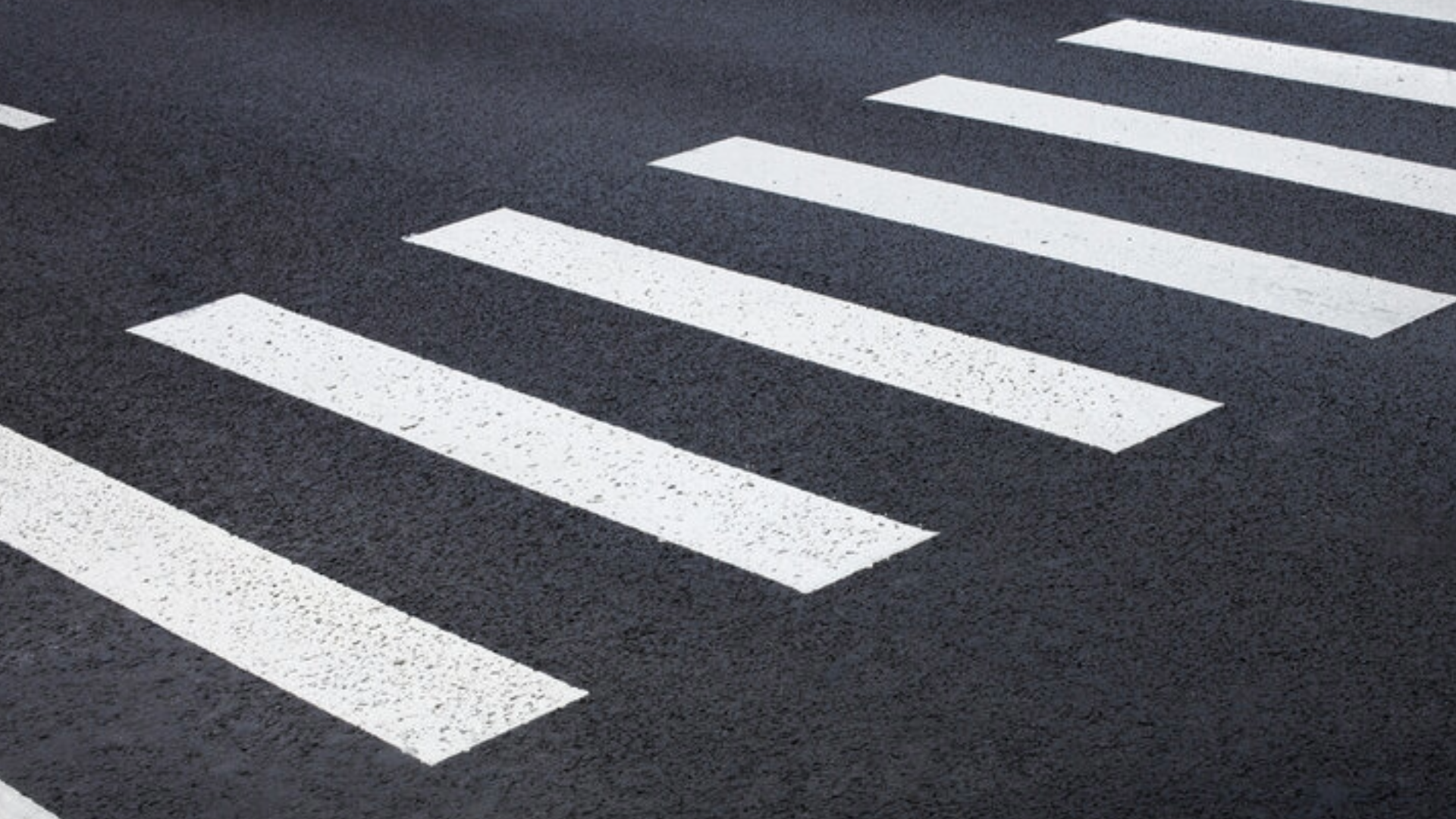 White pedestrian crosswalk stripes on dark asphalt road.