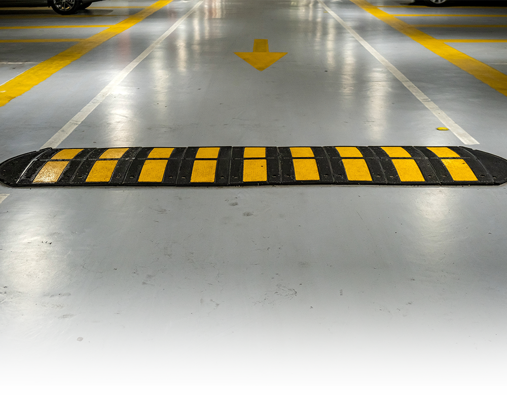 A black and yellow speed bump in a parking garage