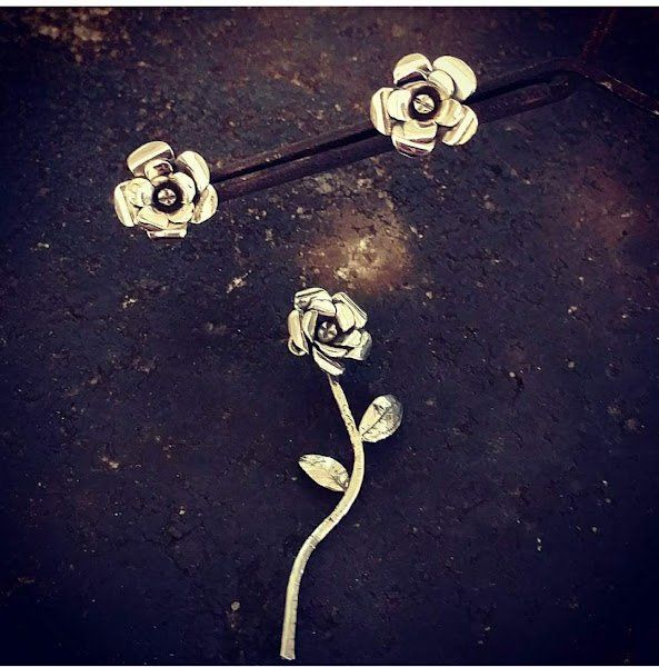 Três rosas prateadas estão sentadas sobre uma superfície preta