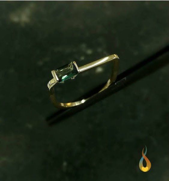 Um anel de ouro com uma pedra verde