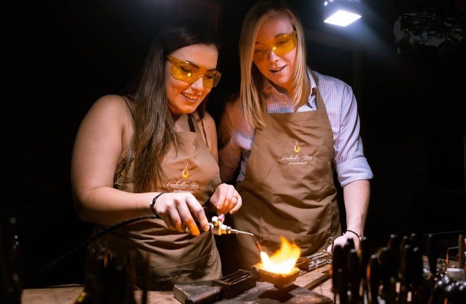 Duas mulheres trabalham em uma peça de metal em uma oficina.