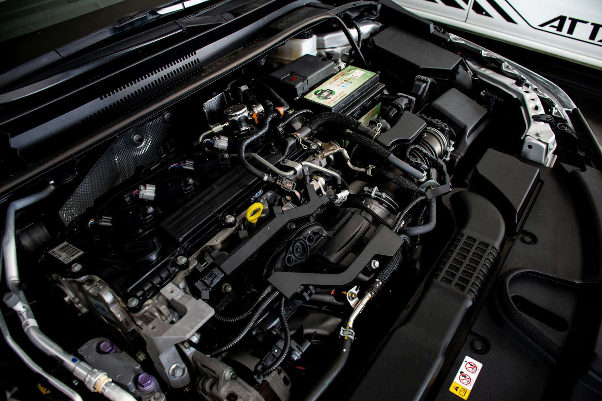 Mechanic working on a car engine, inspecting with a tool.