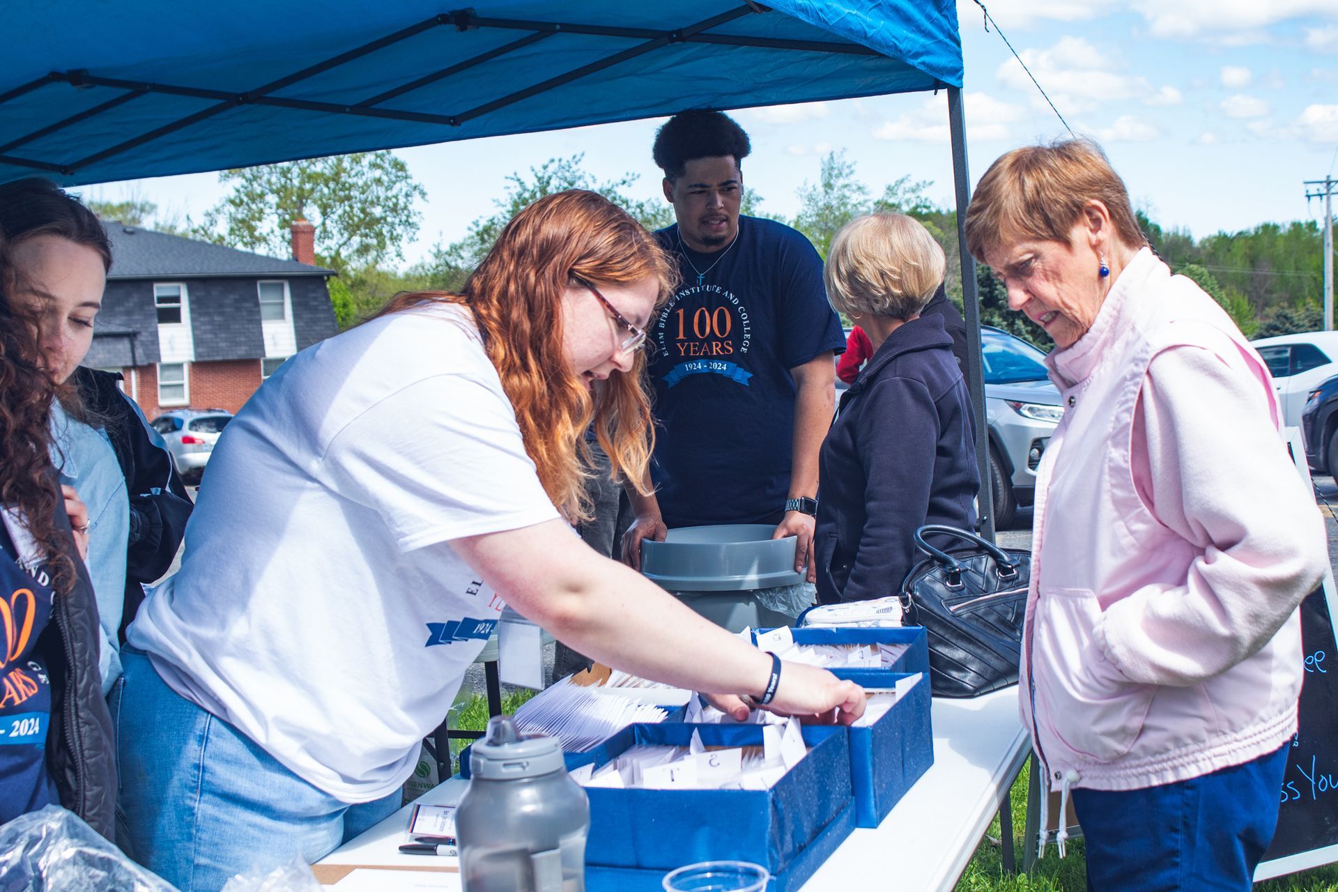 students and staff running a booth during Elim's 100th Anniversary Celebration