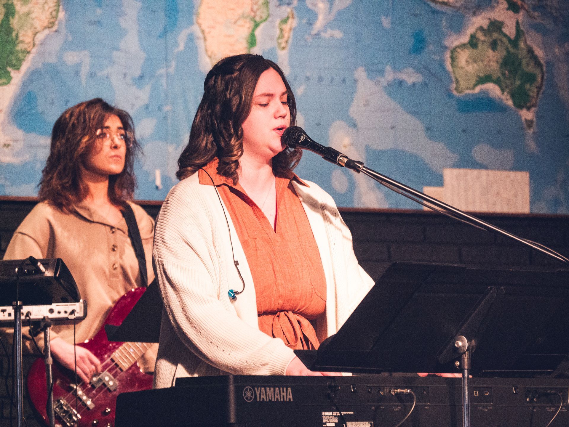 a girl playing piano and singing during chapel