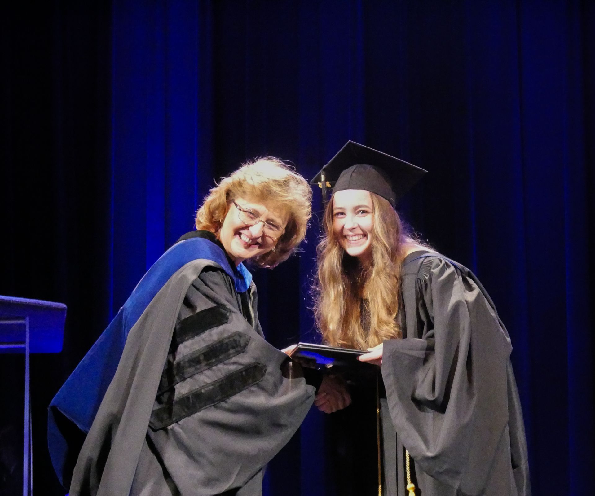 a student receiving a certificate from the provost, smiling