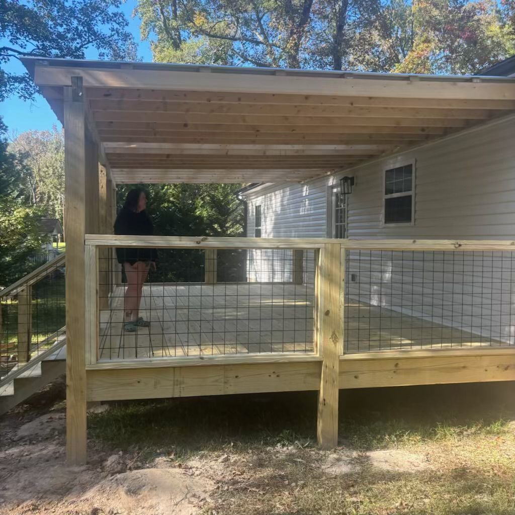 A woman is standing on a wooden deck in front of a house.