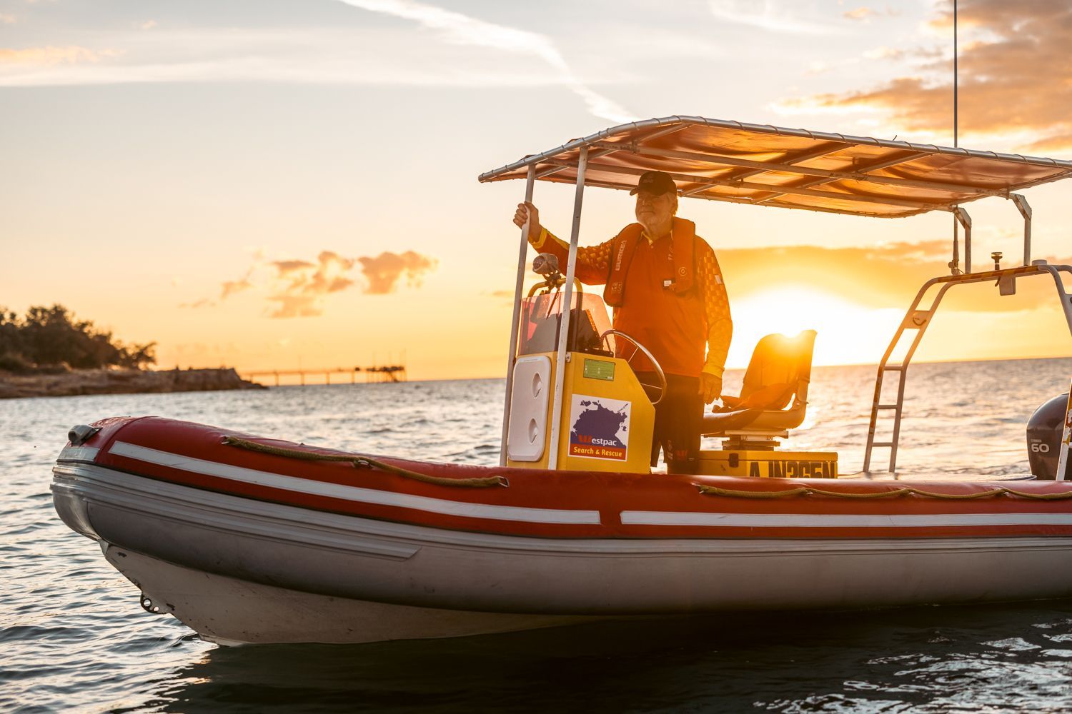 Two people on a small motorboat at sunset on calm water