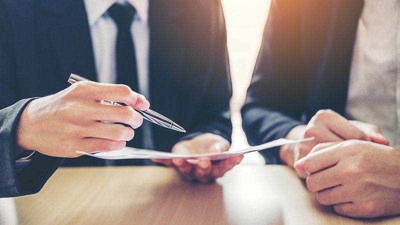man points at paper with a pen