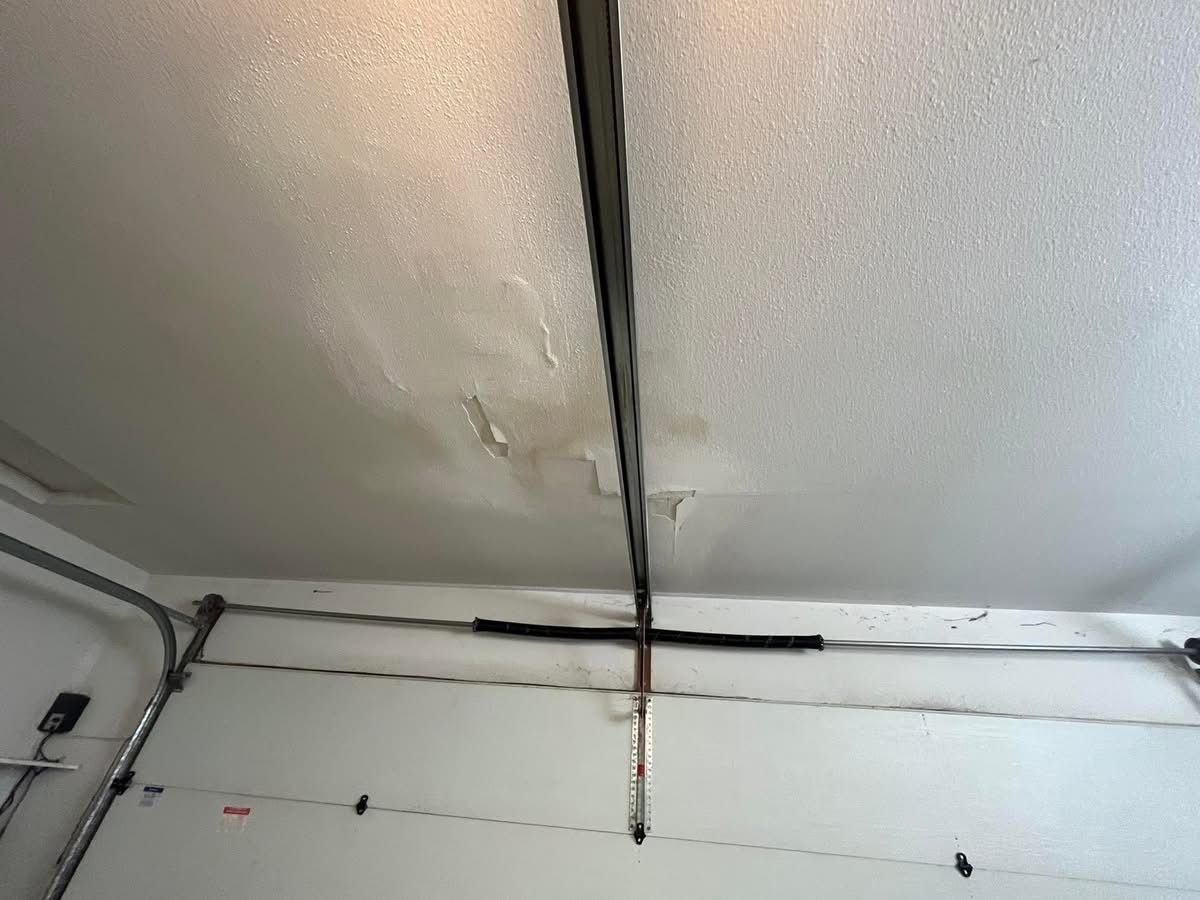Garage ceiling with water damage and dark metal beam running across.