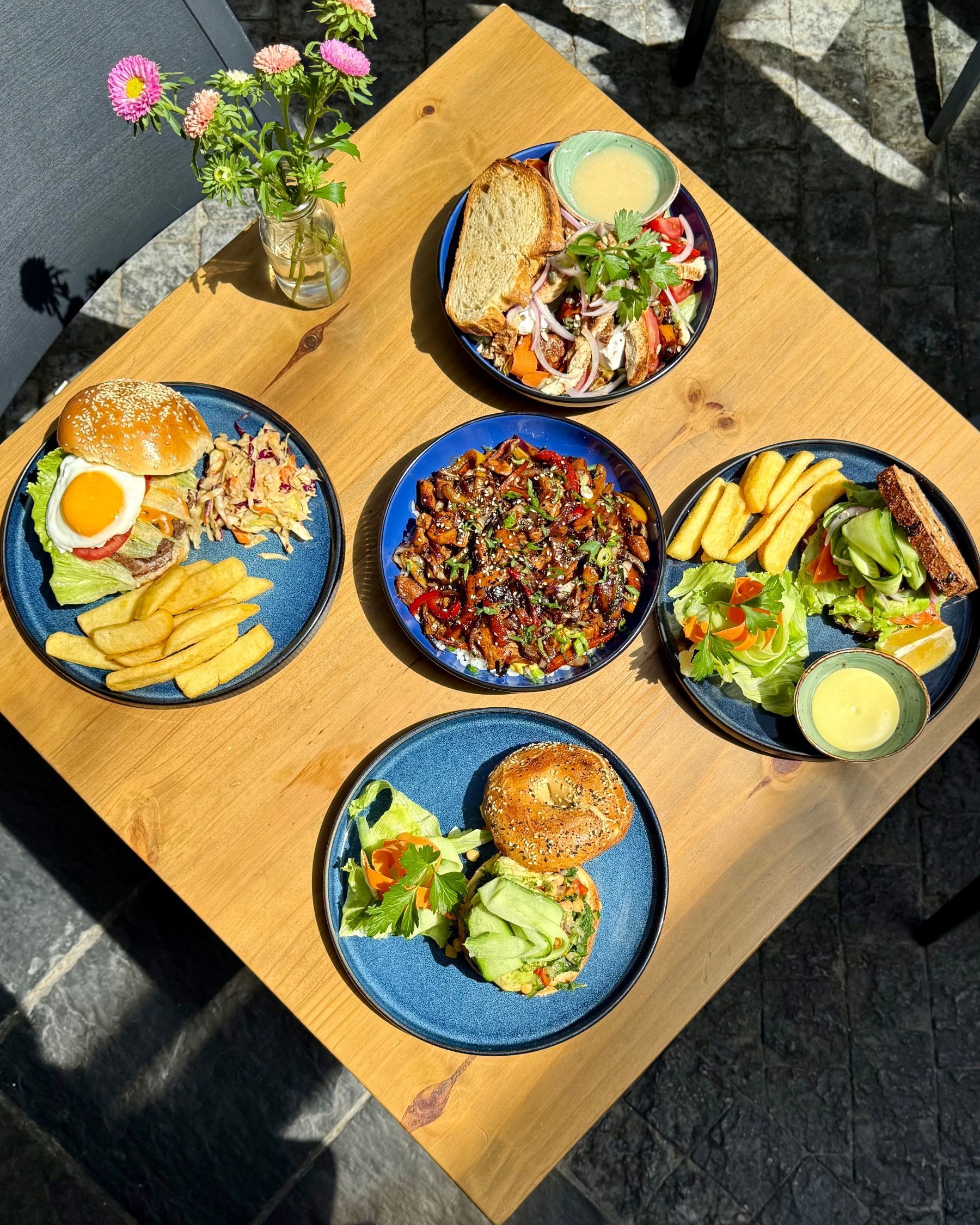 Yumcious a la carte spread with burger, stir fry, salad, sandwich, and bagel