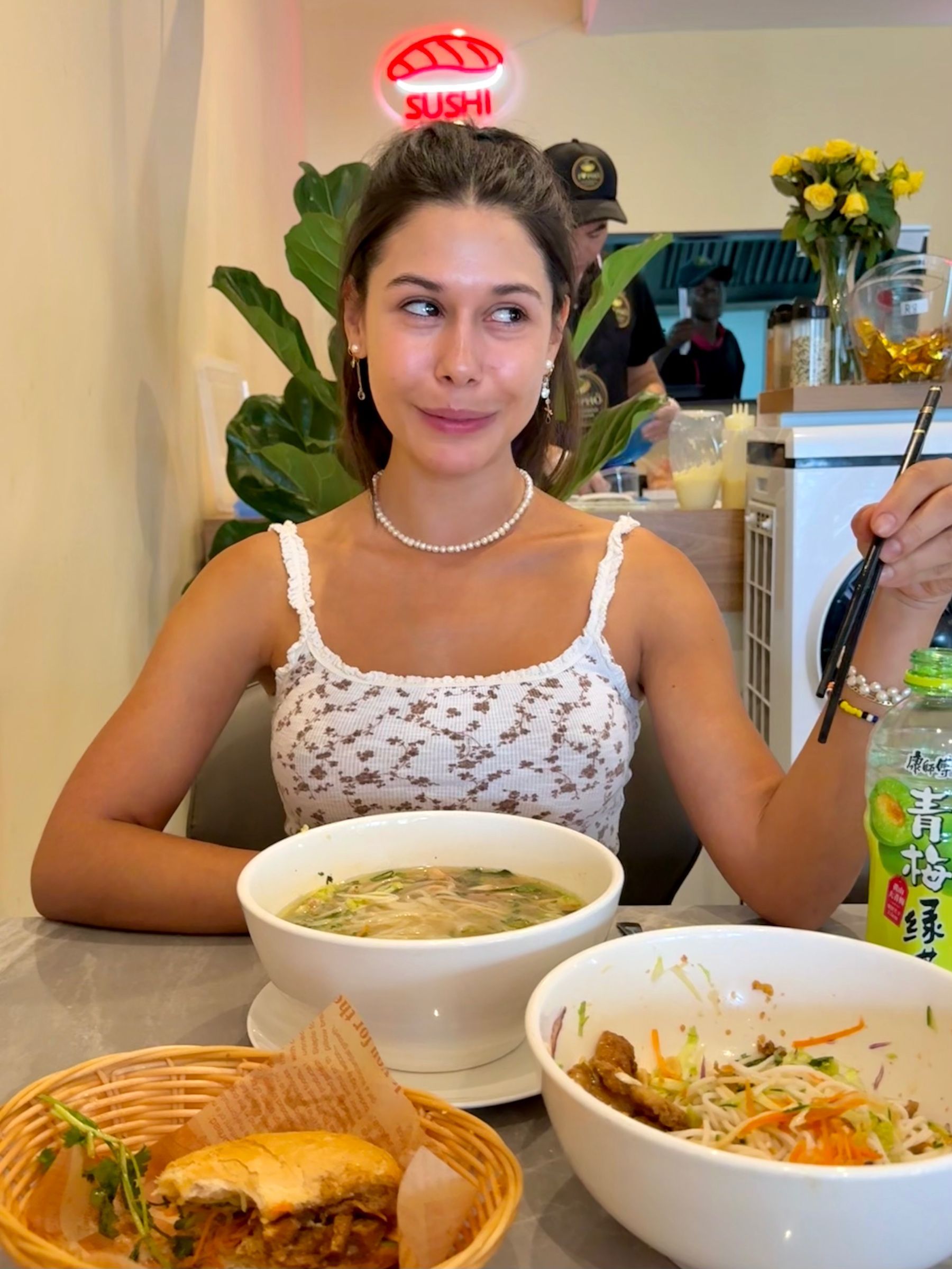Paige holding chopsticks with pho and vermicelli bowls