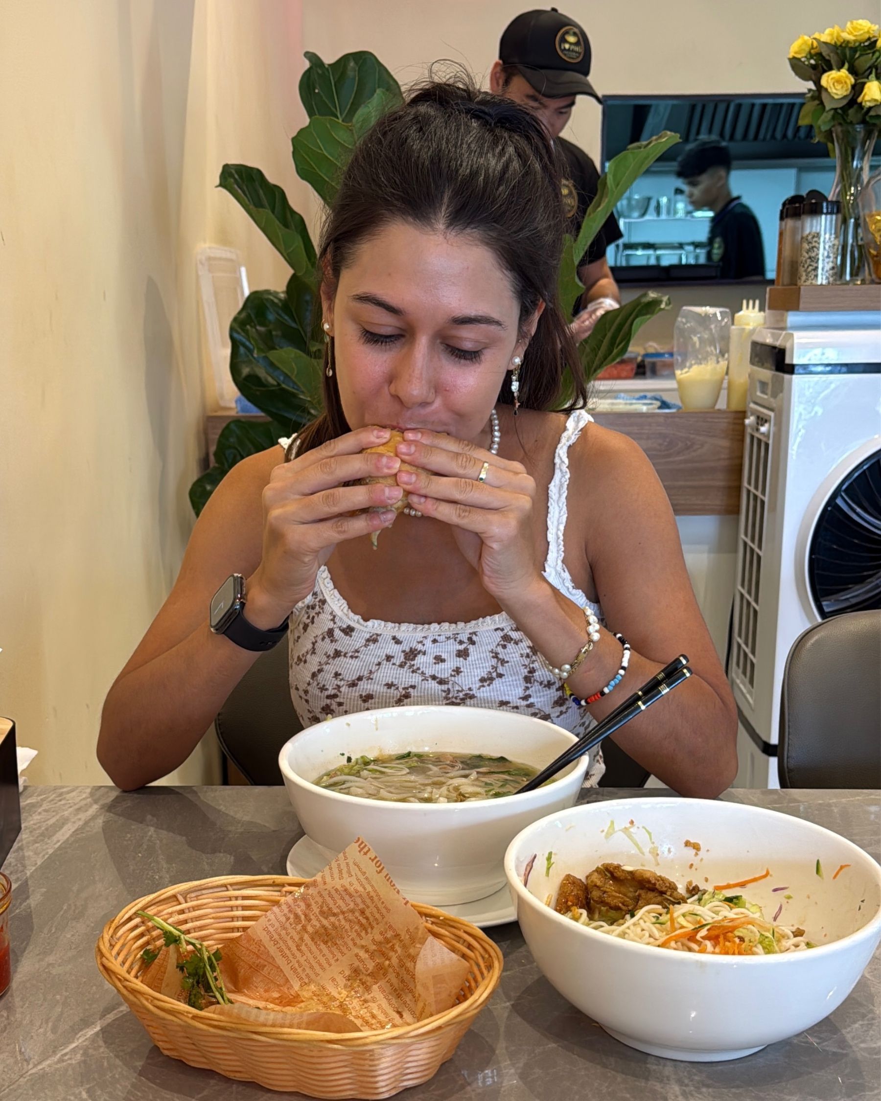 Paige eating banh mi with pho and vermicelli dishes